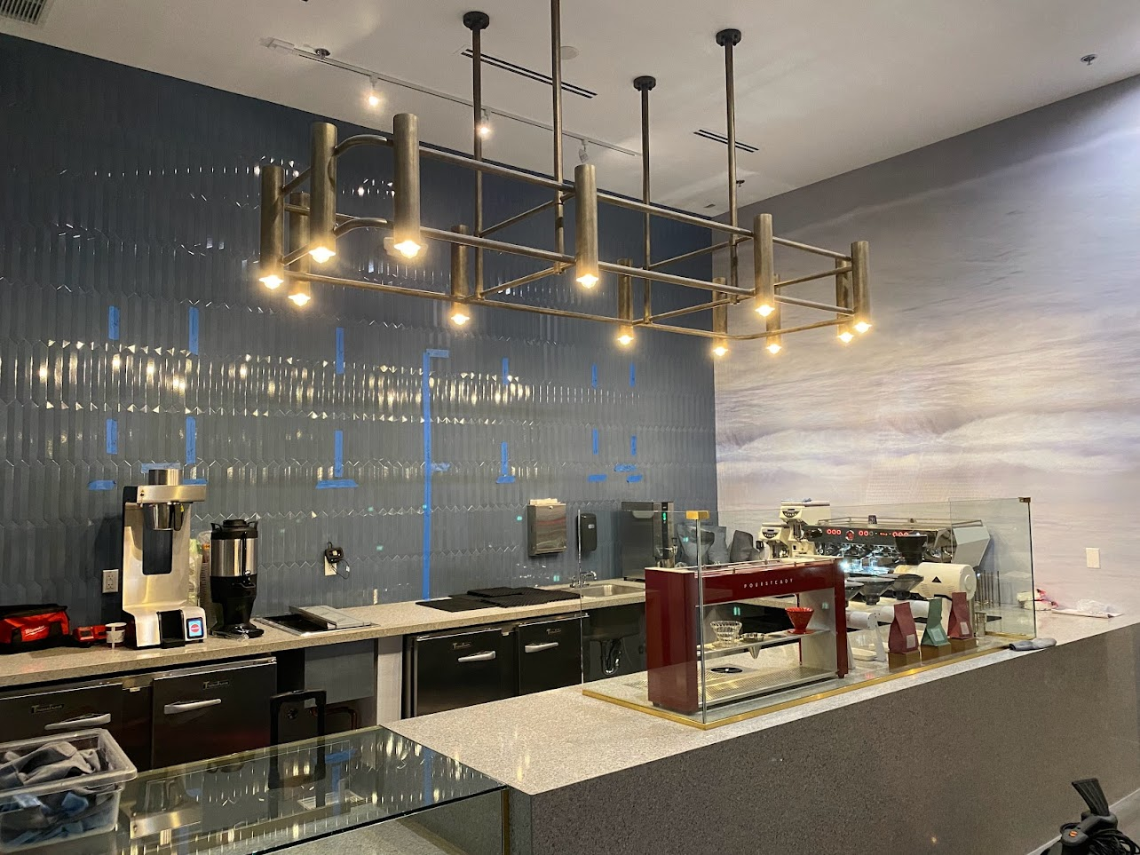 Modern commercial kitchen with industrial lighting and espresso equipment